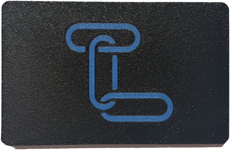 A TapLink card in matte black printed plastic, the TapLink mark across the front in blue, the layer texture of the print visible across the surface